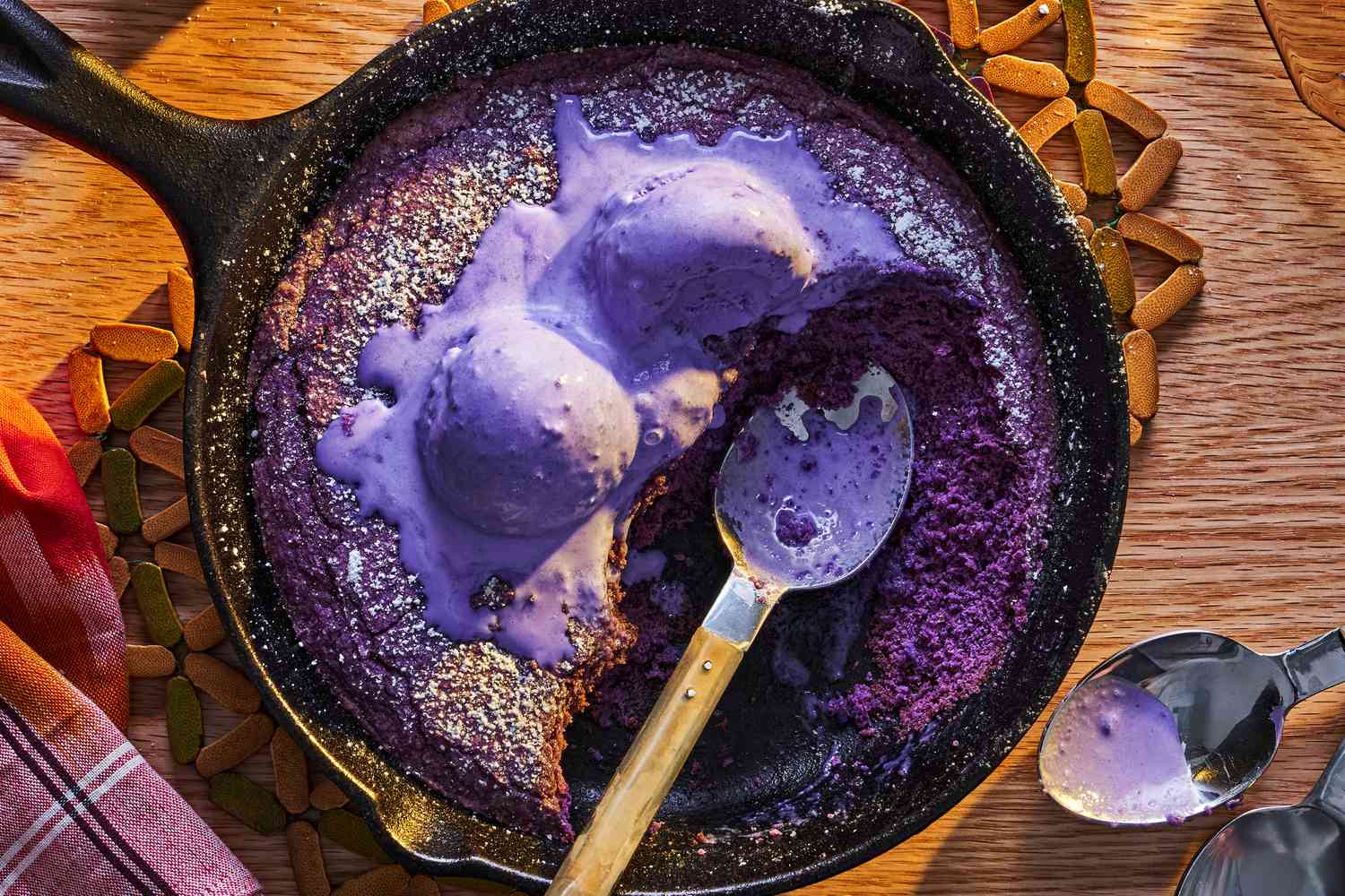 Partially eaten ube skillet cookie topped with ube ice cream, a spoon in the skillet
