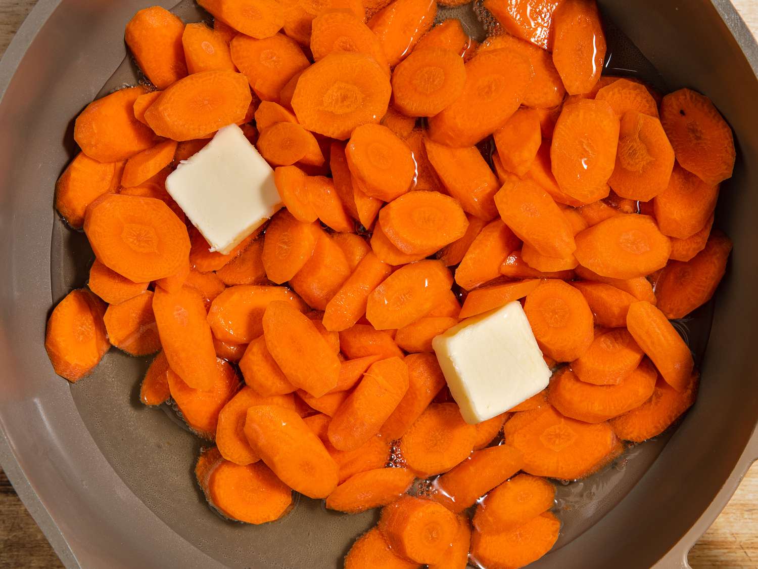 Sliced carrots and butter in a pan