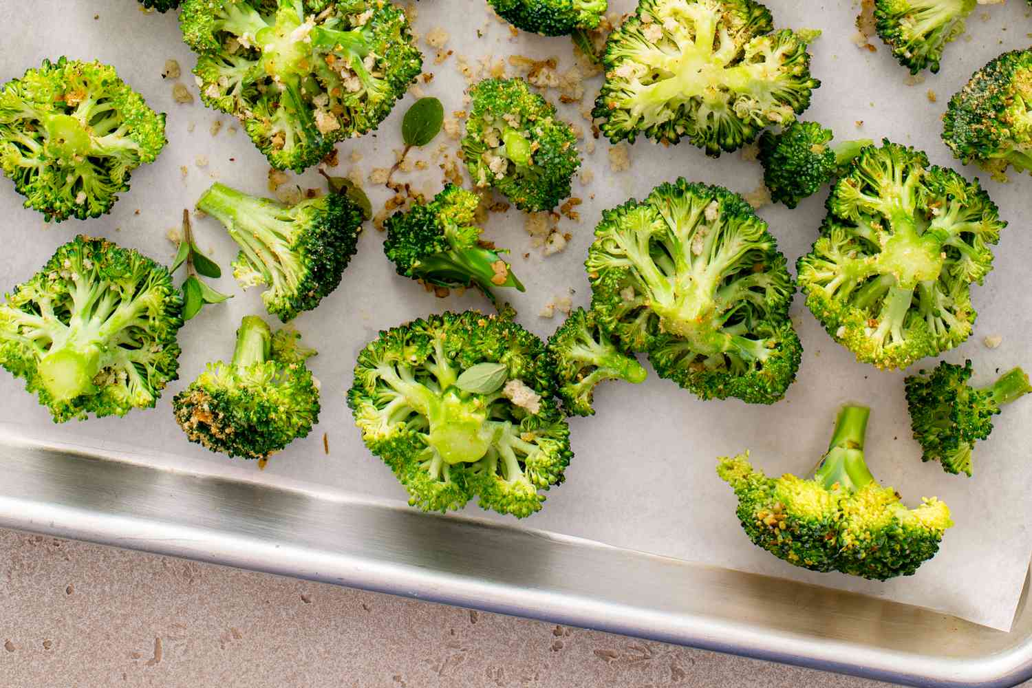 Broccoli florets on a sheet pan ready to be roasted with spices, bread crumbs and olive oil