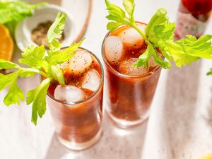 Two glasses of Bloody Mary cocktails with celery garnish on a table