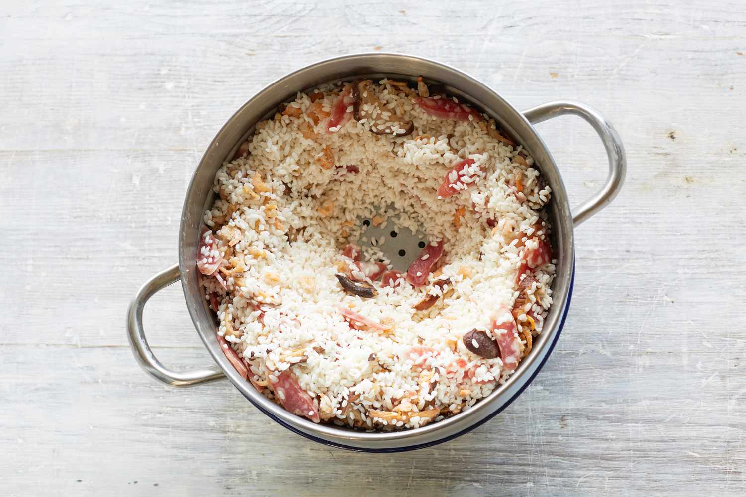 Ingredients in a steamer basket to make steamed rice with sausage, dried shrimp, and mushrooms