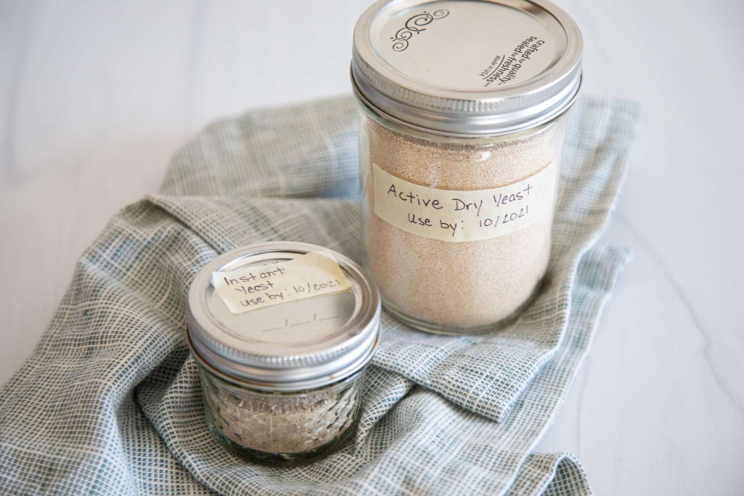 Mason jars with yeast inside set on a linen to show how to store yeast.