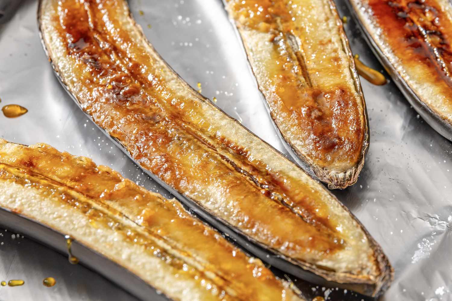 Caramelized banana halves on a baking sheet glistening with syrup