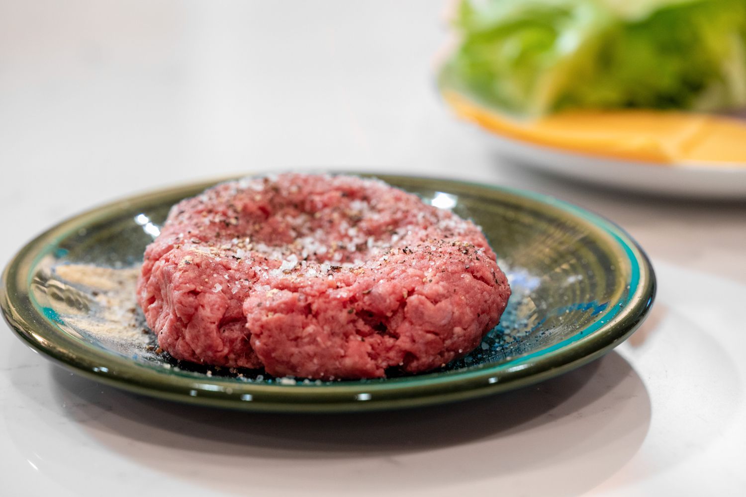 Burger Patty Topped with Seasoning on a Small Plate for How to Make a Burger on the Stove