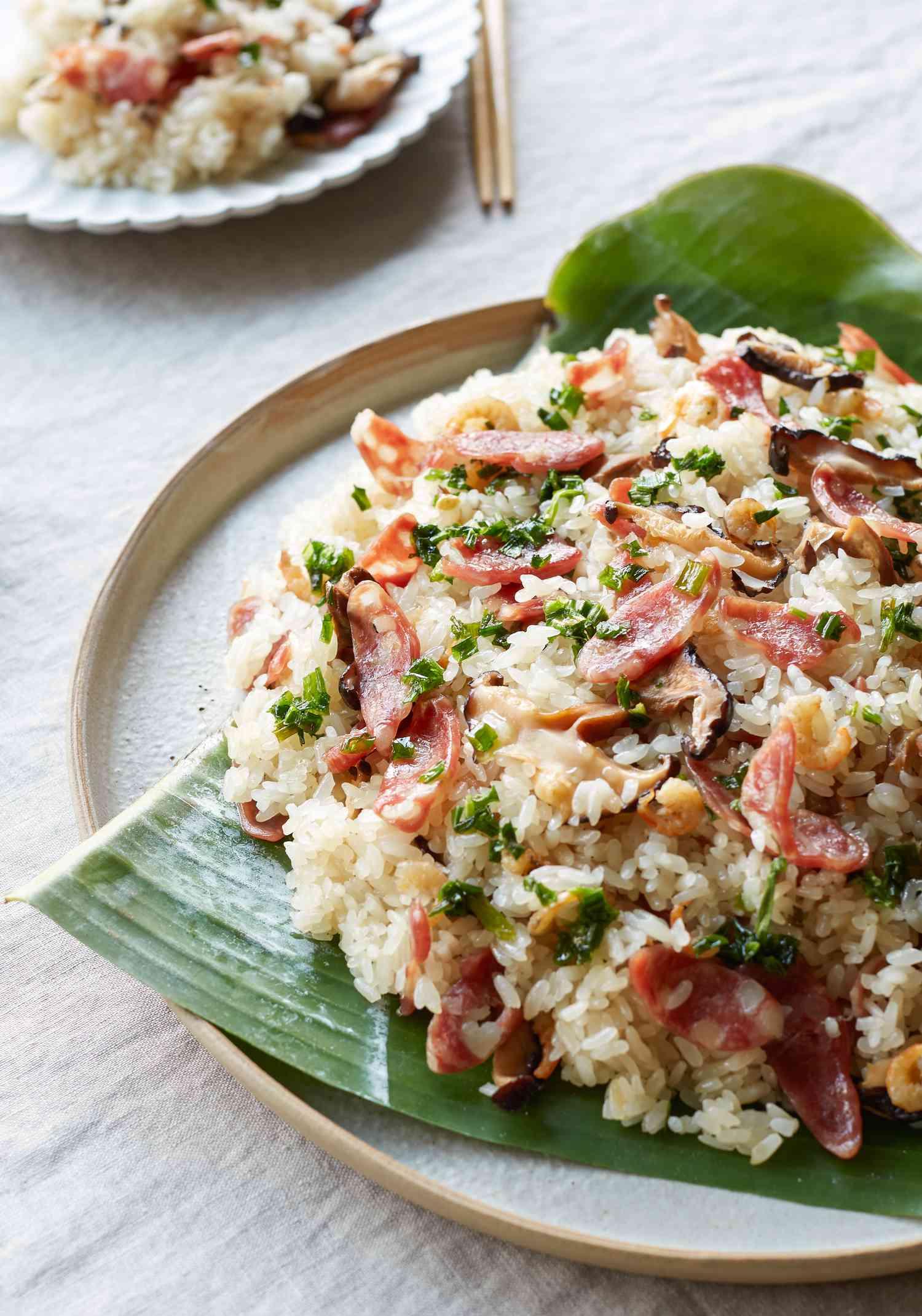 Vietnamese steamed rice on a banana leaf and with a smaller plate of rice behind it.