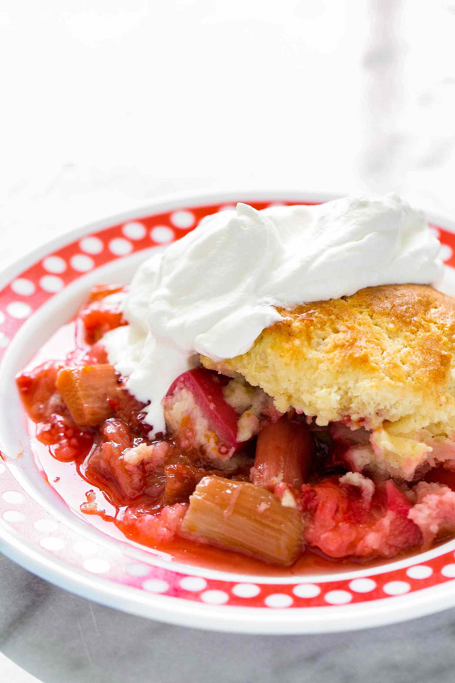 Bowl of Strawberry Rhubarb Cobbler Topped With Whipped Cream