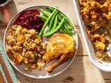 Thanksgiving dinner plate with roasted turkey stuffing green beans and cranberry sauce alongside a dish of extra stuffing