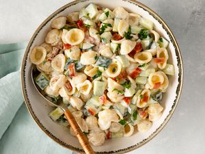 A bowl of pasta salad with bacon cucumber and ranch dressing with a fork