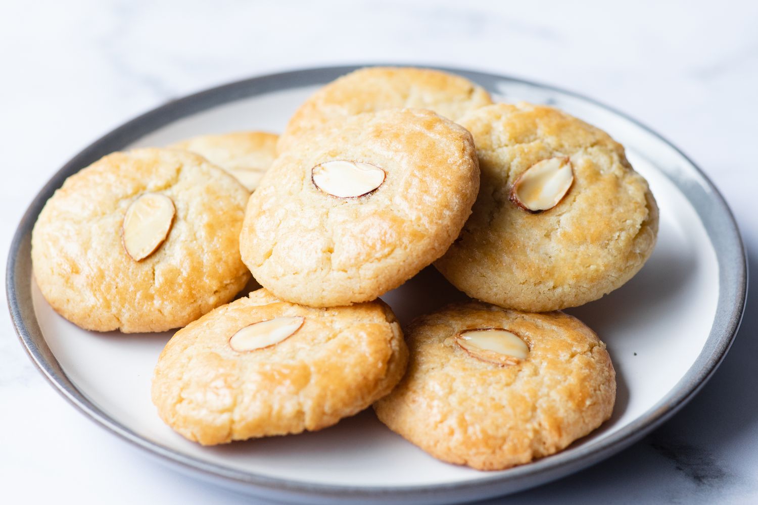 Almond cookies scattered on a rimmed plate.
