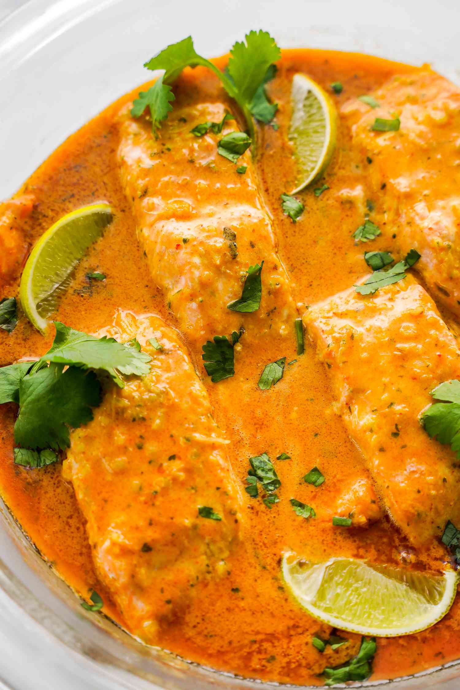 Microwave Red Curry Poached Salmon Topped with Cilantro and Lime Wedges in a Microwavable Glass Bowl