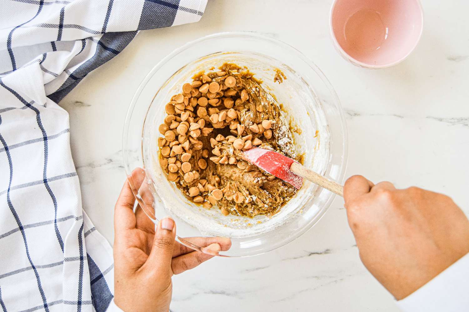Mixing dough with butterscotch chips in a glass bowl