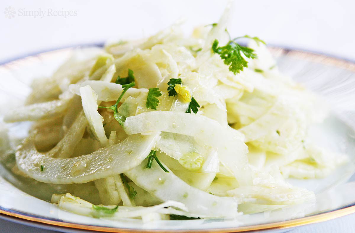 A pile of thinly shaved fennel dressed as a salad on a plate.