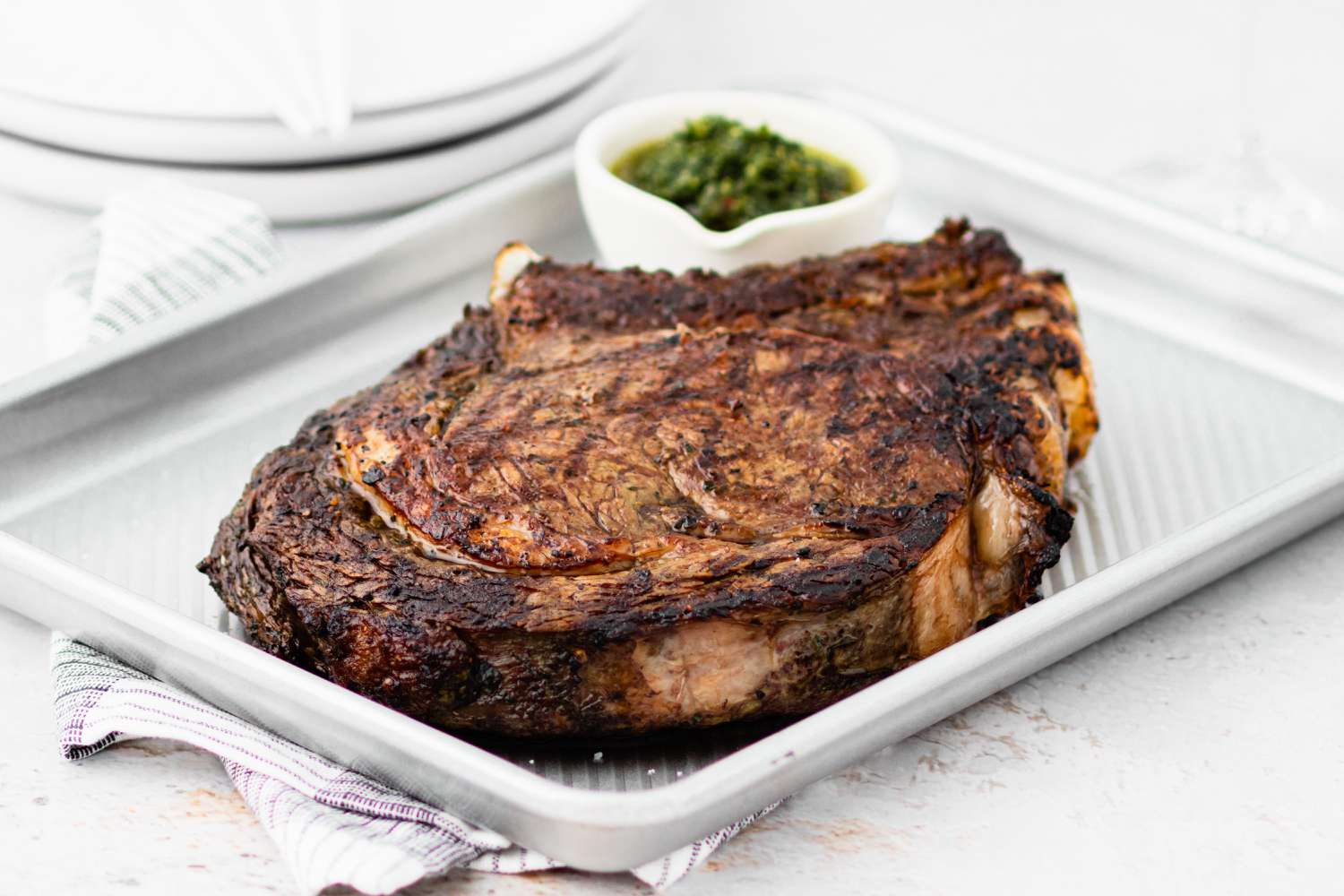 A baking sheet with cowboy steak and sauce.