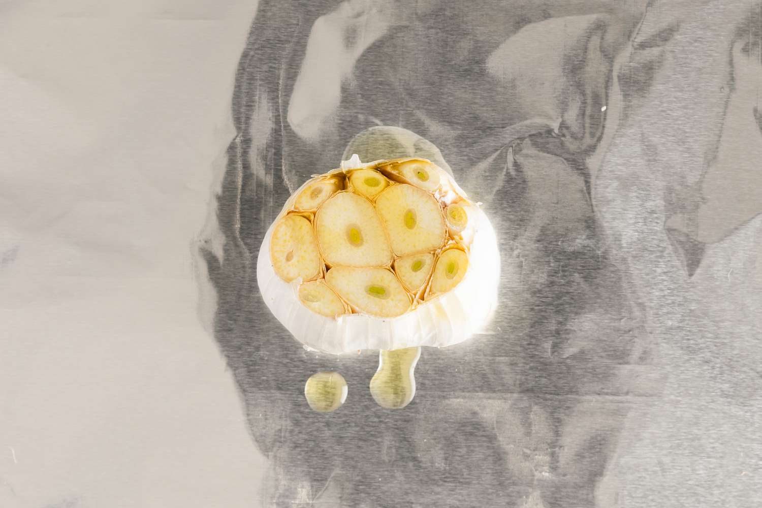 Trimmed garlic on a piece of foil, drizzled with oil