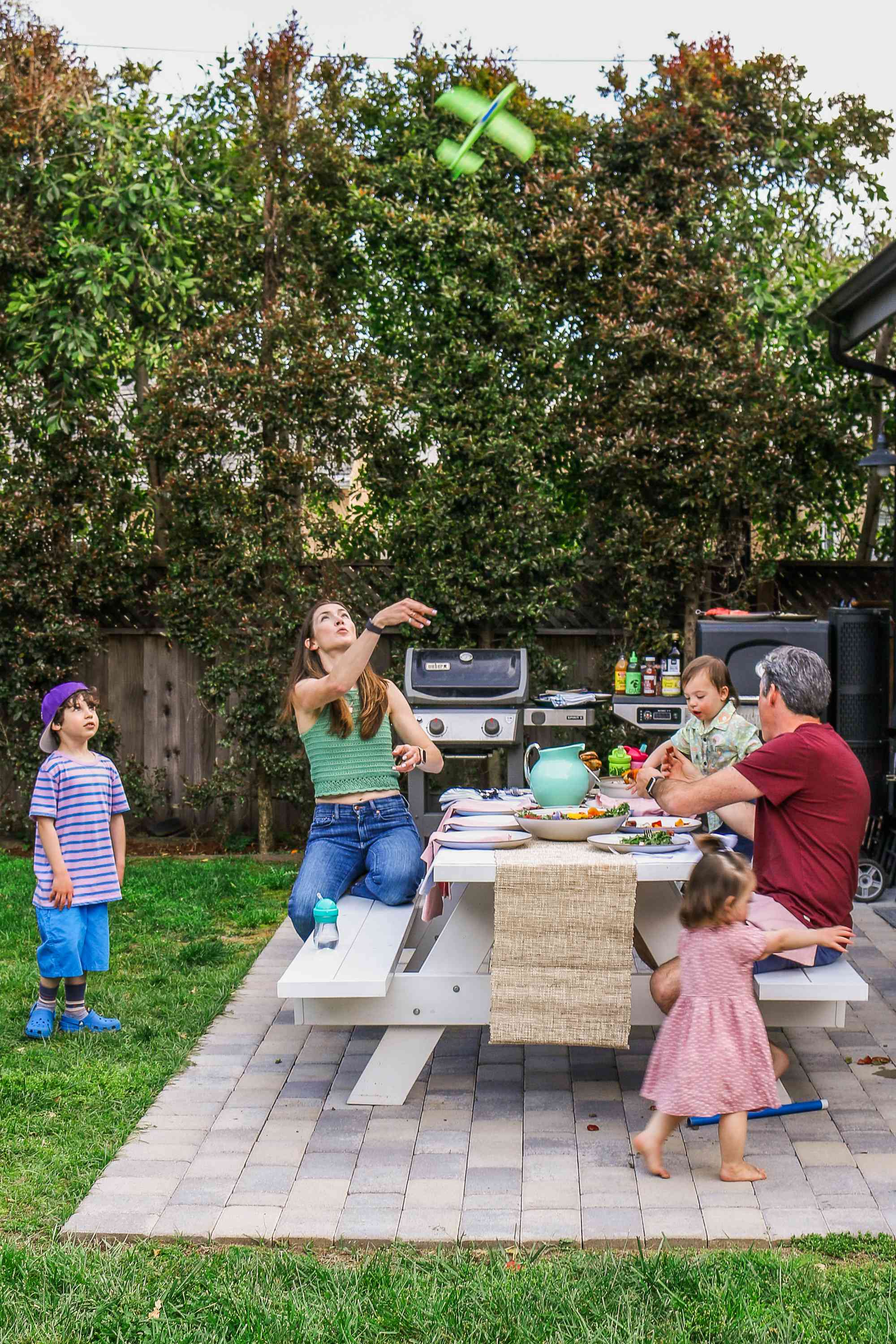 The Pfeffer family around the outdoor picnic table, a toy airplane soaring