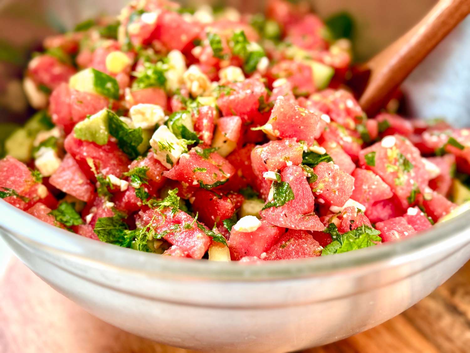 A bowl of salad with watermelon, avocado, and herbs mixed together
