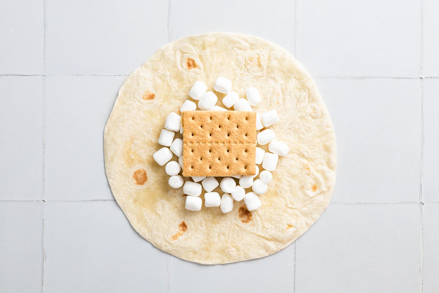 Graham Cracker Placed on Top of the Mini Marshmallows for S'mores Crunchwrap Recipe