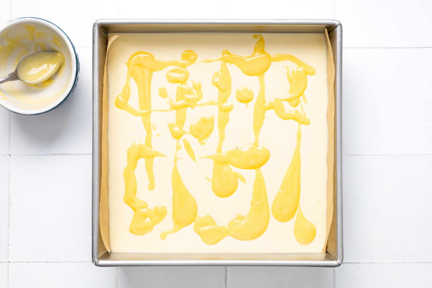 Lemon Curd Poured Over Lemon Cheesecake Bar Filling in the Lined Baking Pan 