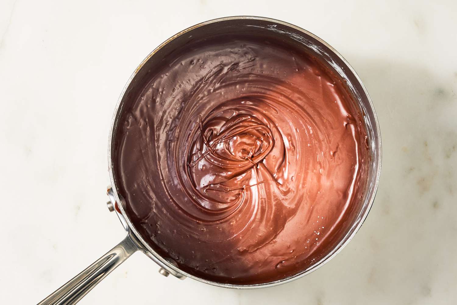 Overhead view of a saucepan of frosting after adding the butter and cocoa to the reduced cola for Coca Cola Cake recipe
