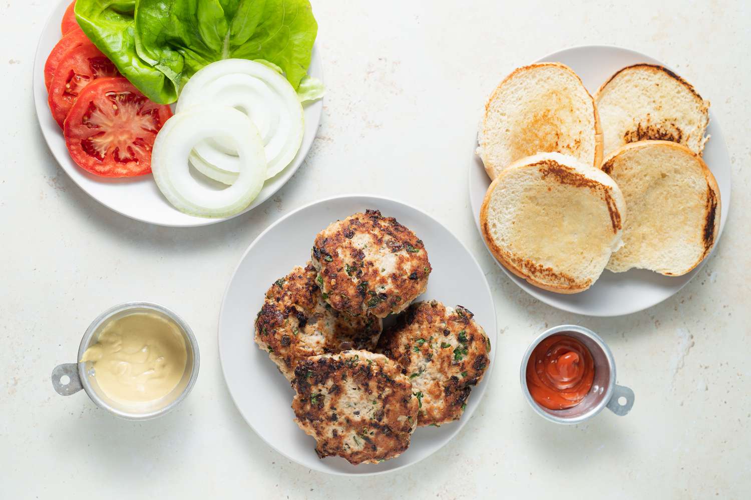 Plates with toasted buns, turkey burgers, and toppings for the best turkey burger recipe.