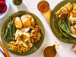 Plates with turkey green beans mashed potatoes corn and gravy seen from above