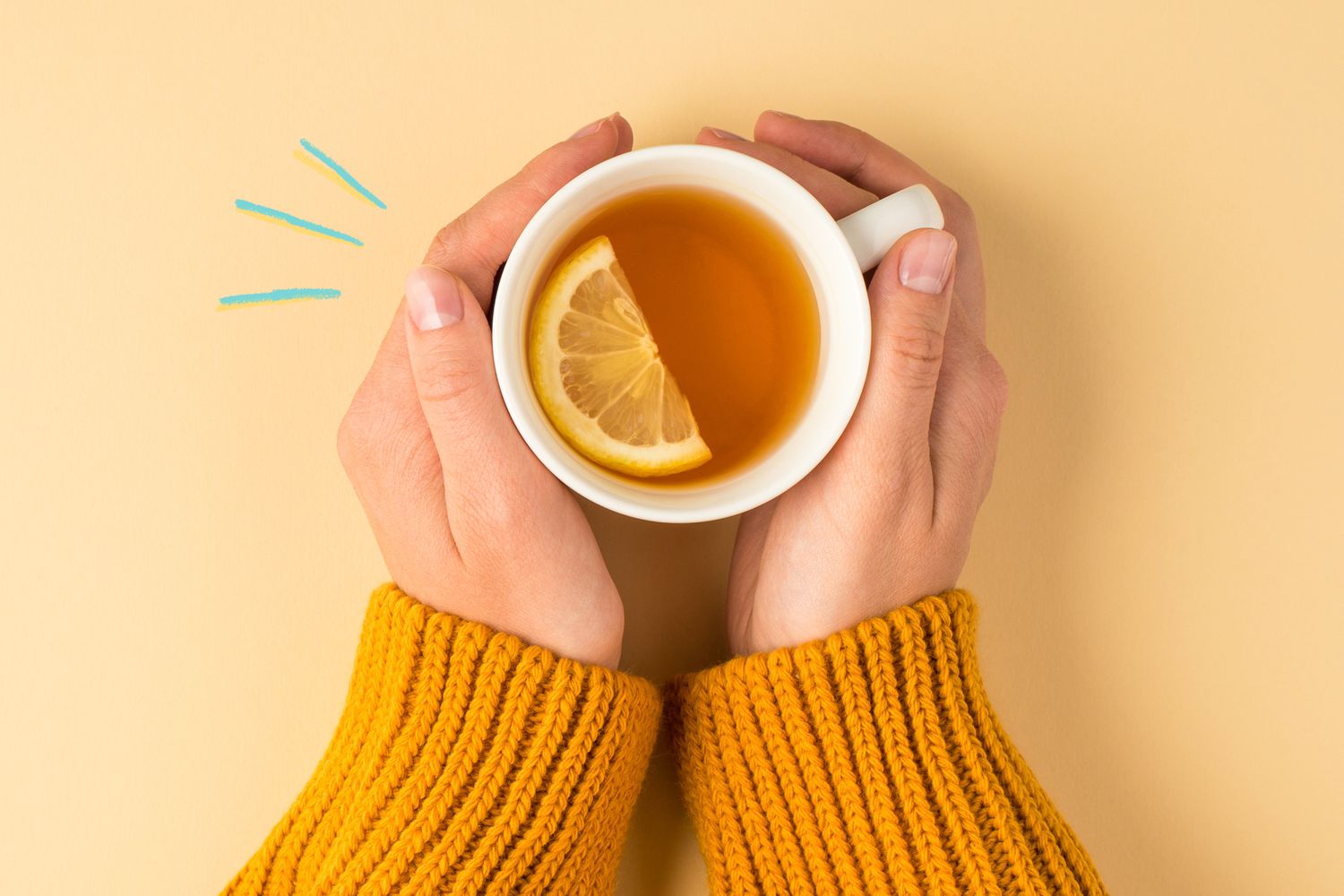 Hands holding a cup of tea with a slice of lemon