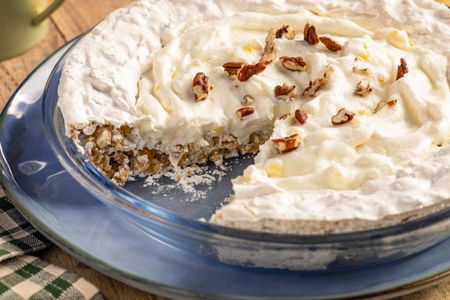 A cream pie with nuts in a blue dish one slice removed