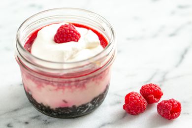 Raspberry cheesecake in a jar topped with whipped cream and fresh raspberry