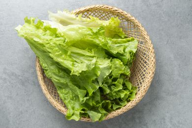 Romaine lettuce in a wicker basket arranged on a gray surface