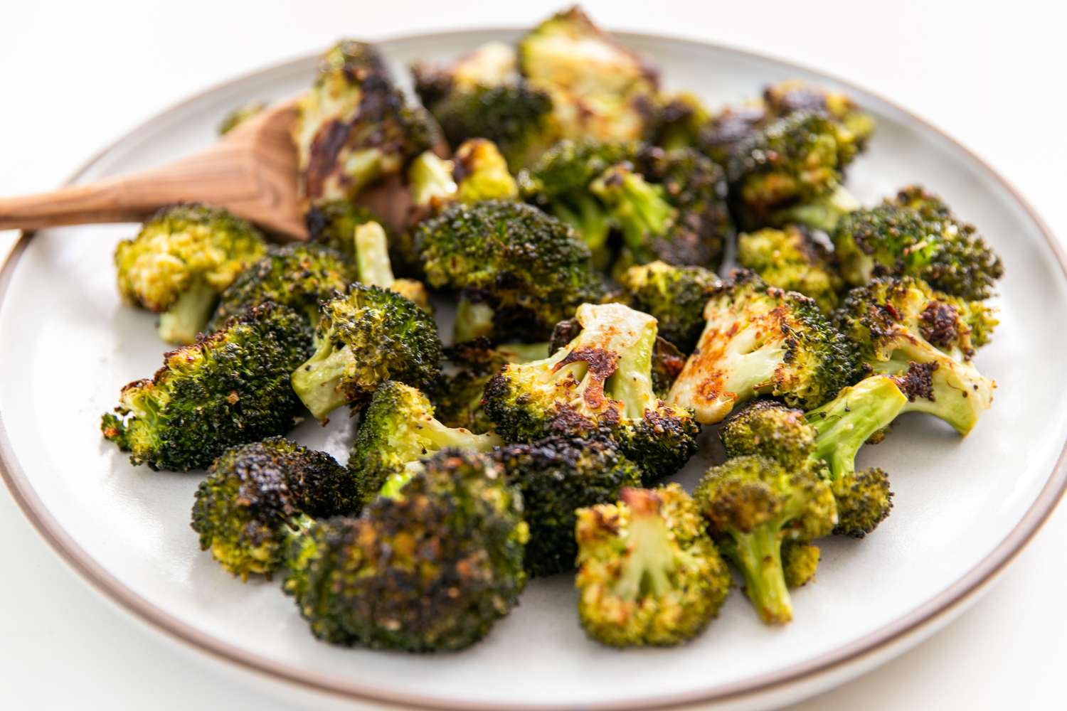 Plated roasted broccoli pieces with a fork