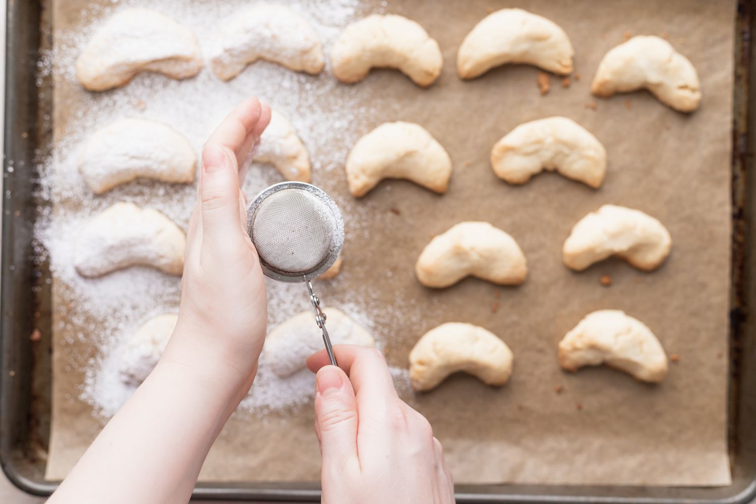 Dusting almond flour sugar cookies with powdered sugar.