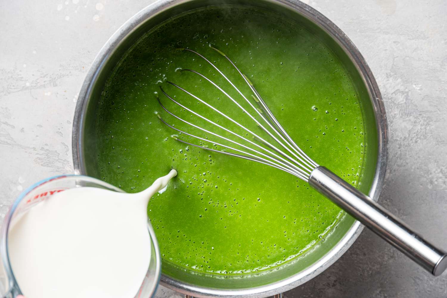 Adding cream to a pot of Cream of Spinach Soup