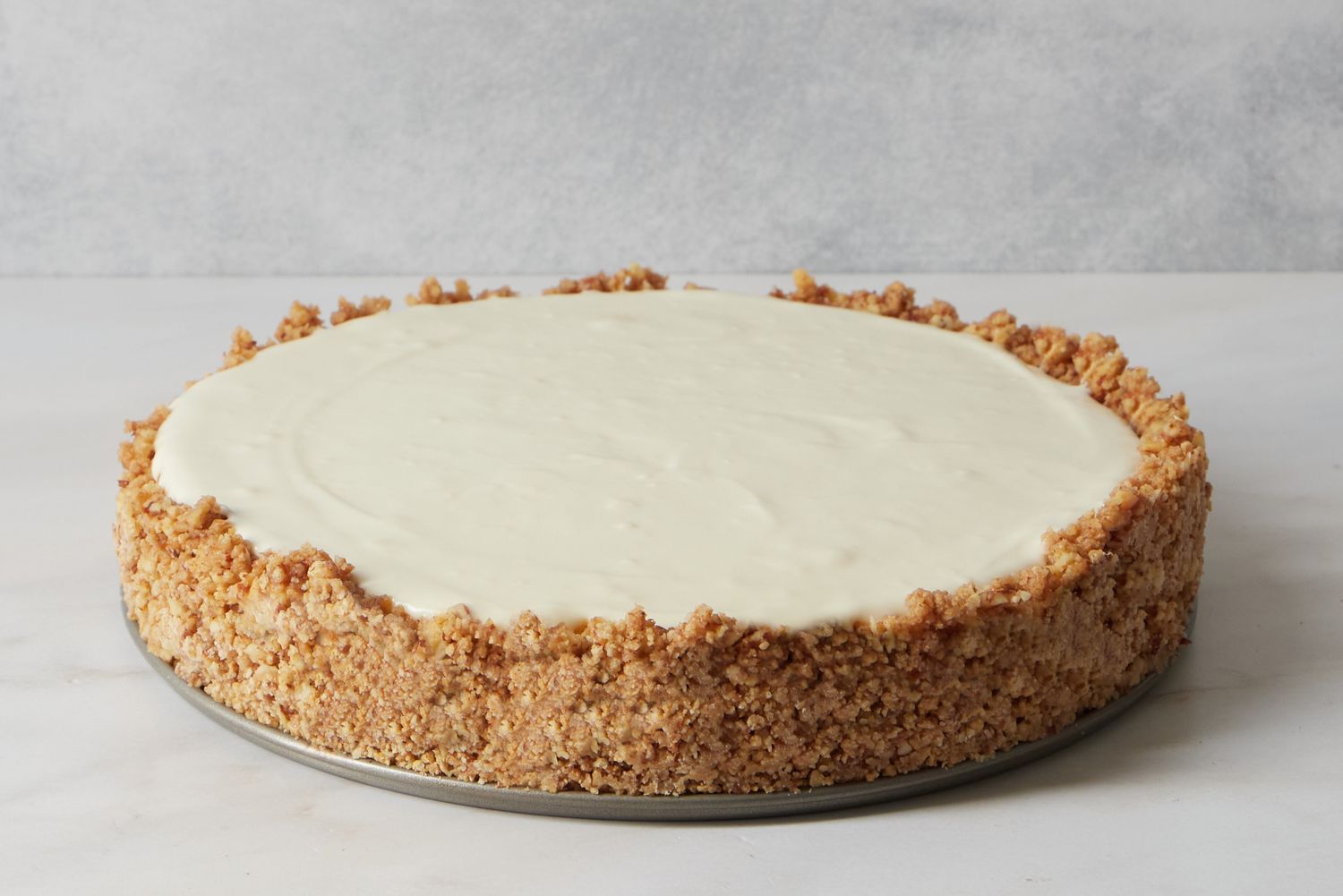 A nobake cheesecake on a crusty base set on a marble surface