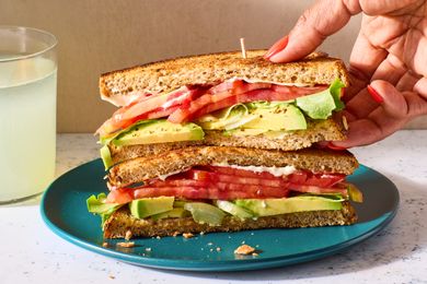 A sandwich with sliced tomatoes, avocado, butter lettuce, and mayonnaise on toasted whole-wheat bread