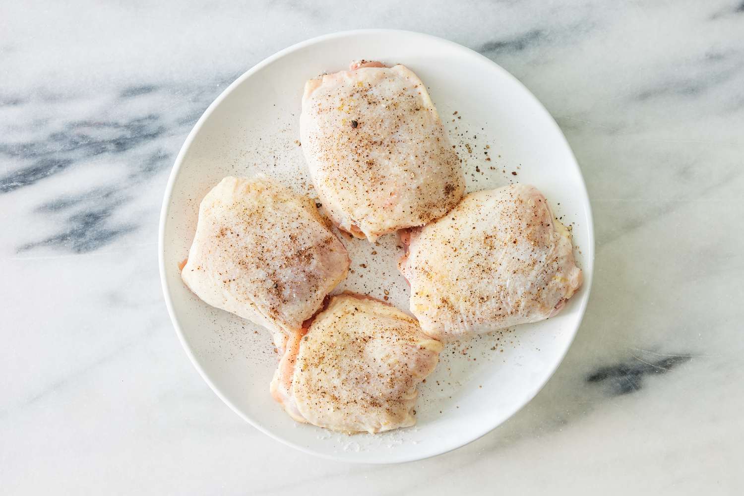 seasoned chicken thighs on a plate for crispy chicken thighs with zucchini and shallots recipe