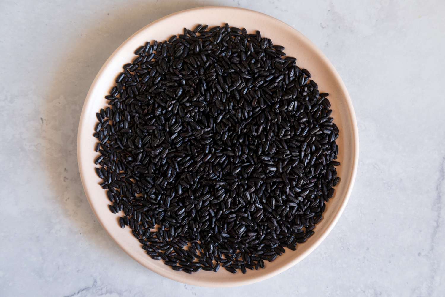 Black rice on pale pink plate
