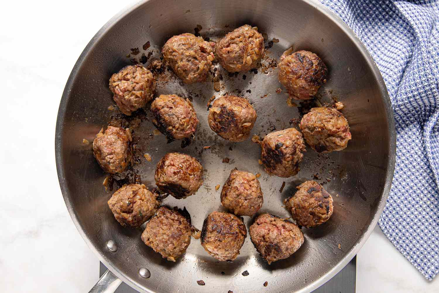 Cooked Meatballs for French Onion Meatballs in a Pan on the Portable Stovetop, and on the Counter Next to It, a Blue Kitchen Towel 