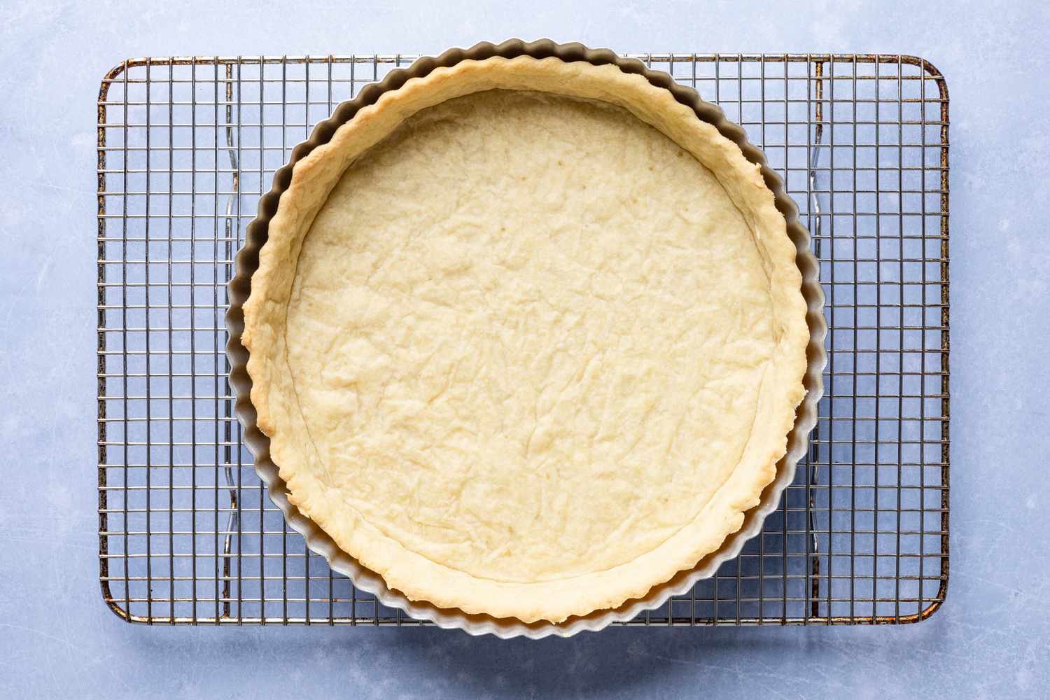 blind baked crust in tart pan on a cooling rack for cornflake tart recipe
