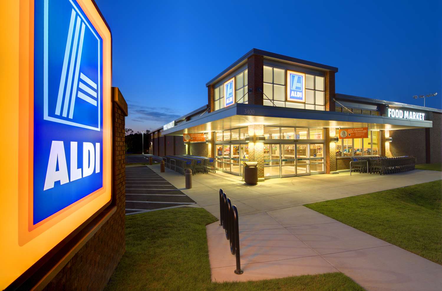Exterior view of an Aldi grocery store at dusk with lit signage and parking area