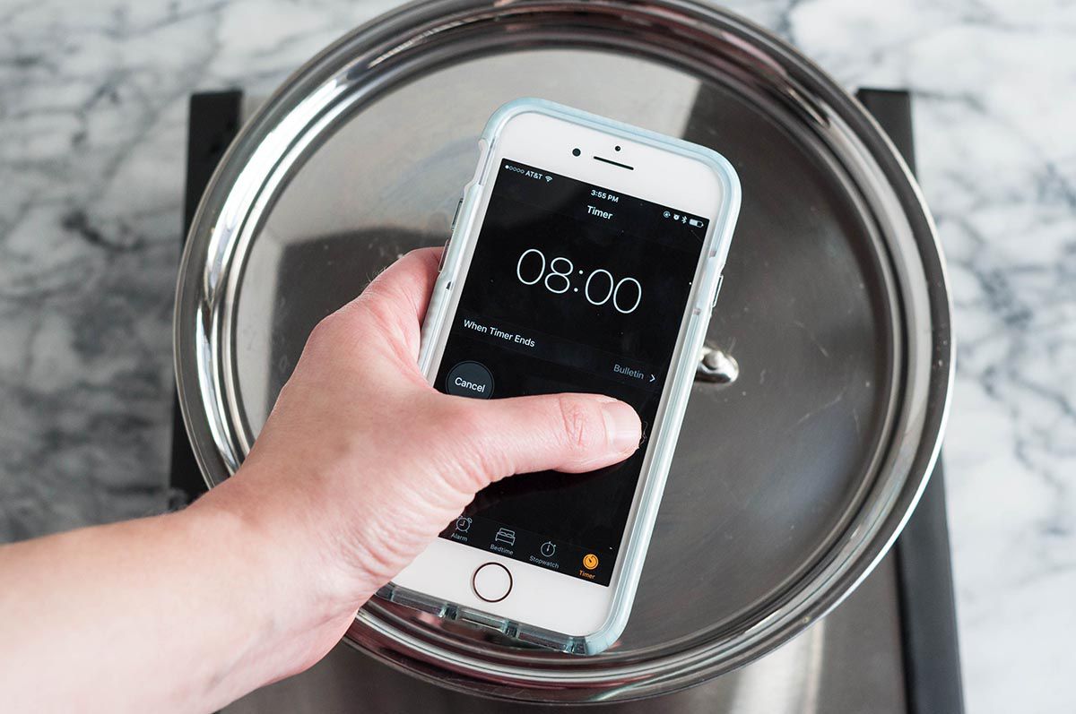 A hand setting a timer on a phone to 8 minutes