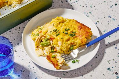 Angled view of a white plate of super easy chicken cobbler and fork on a speckled countertop