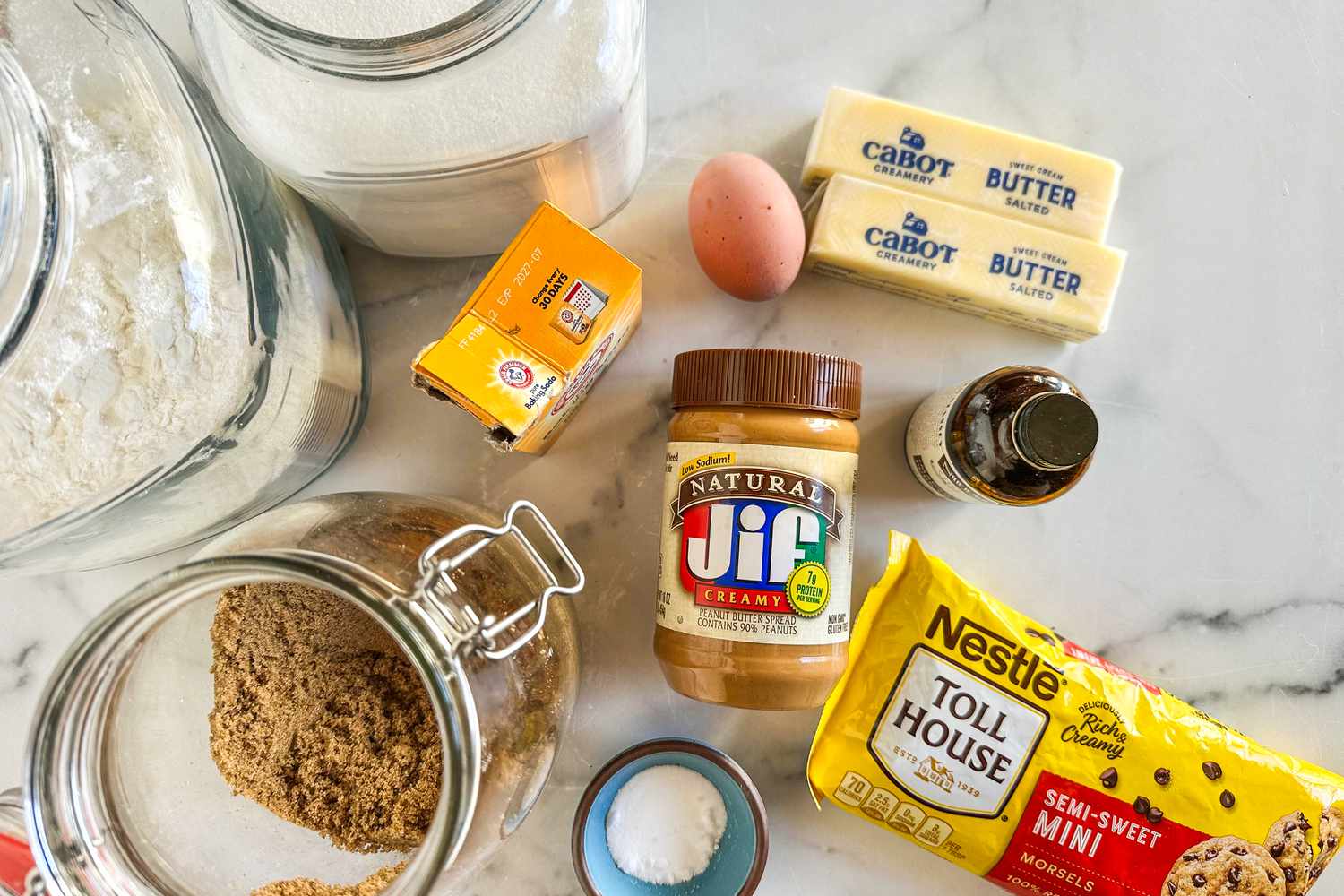 Overhead view of ingredients for chocolate chip cookies spread out on a marble countertop