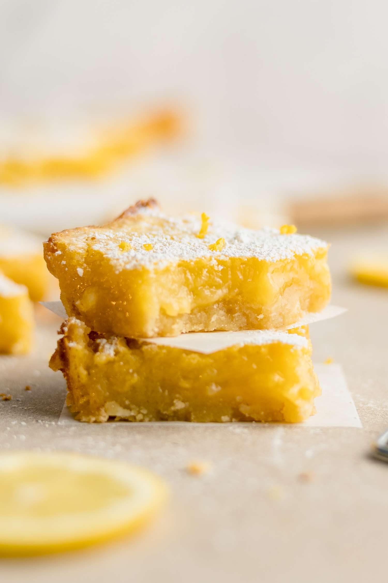 Stack of Two Lemon Bars Next to a Slice of Lemon