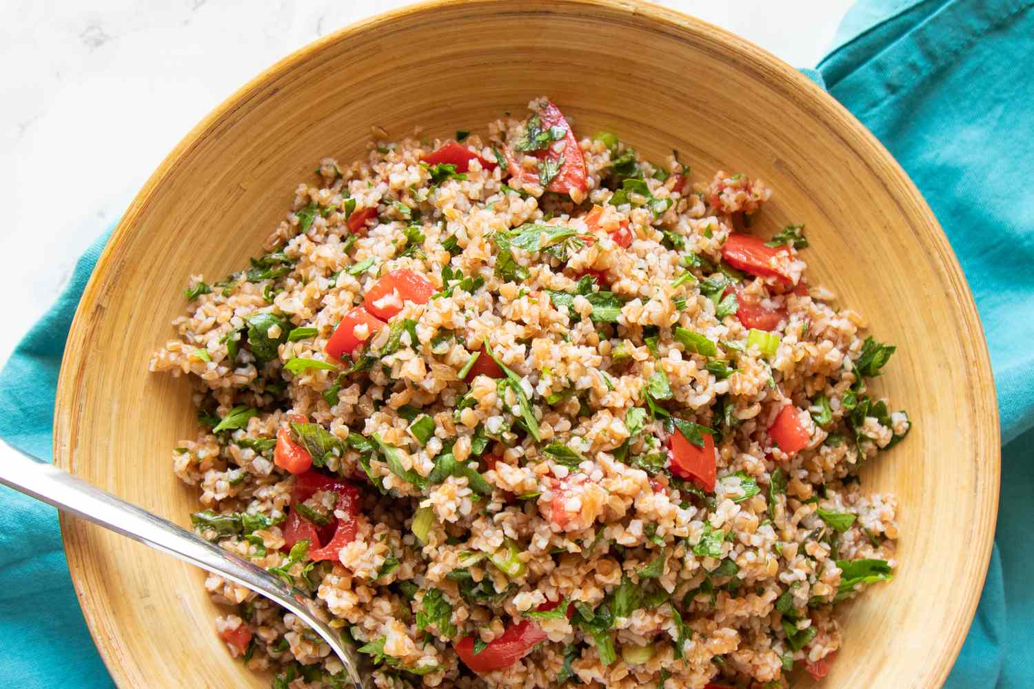 Tan bowl with tabbouleh and a spoon.