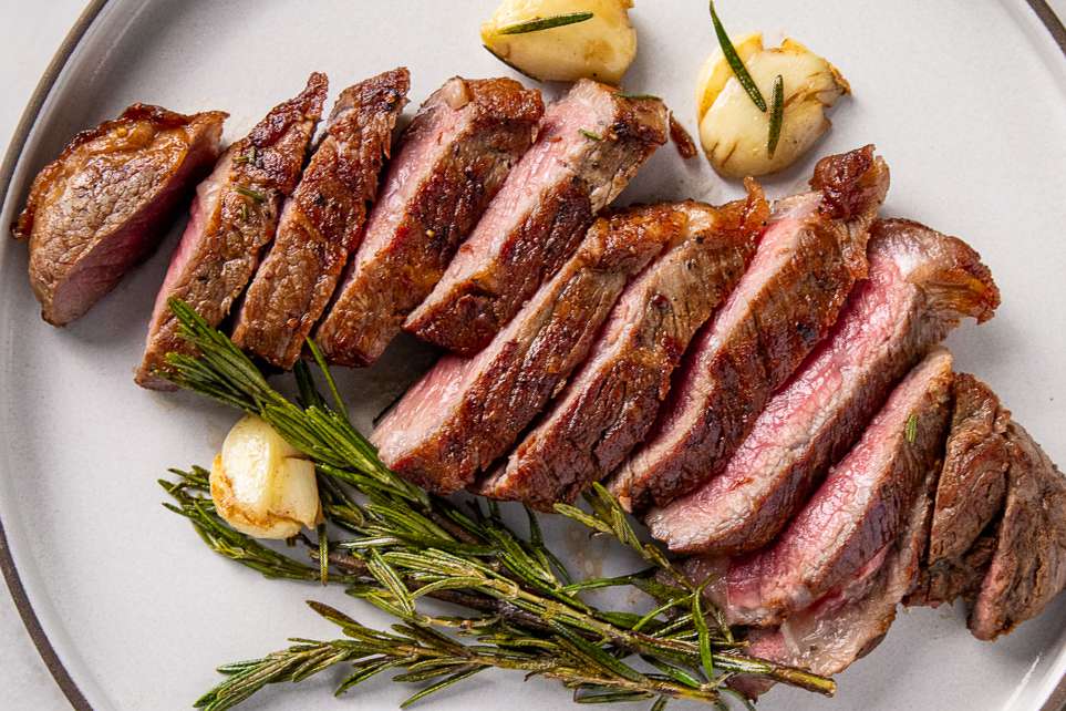 Sliced steak served with herbs and garlic on a plate