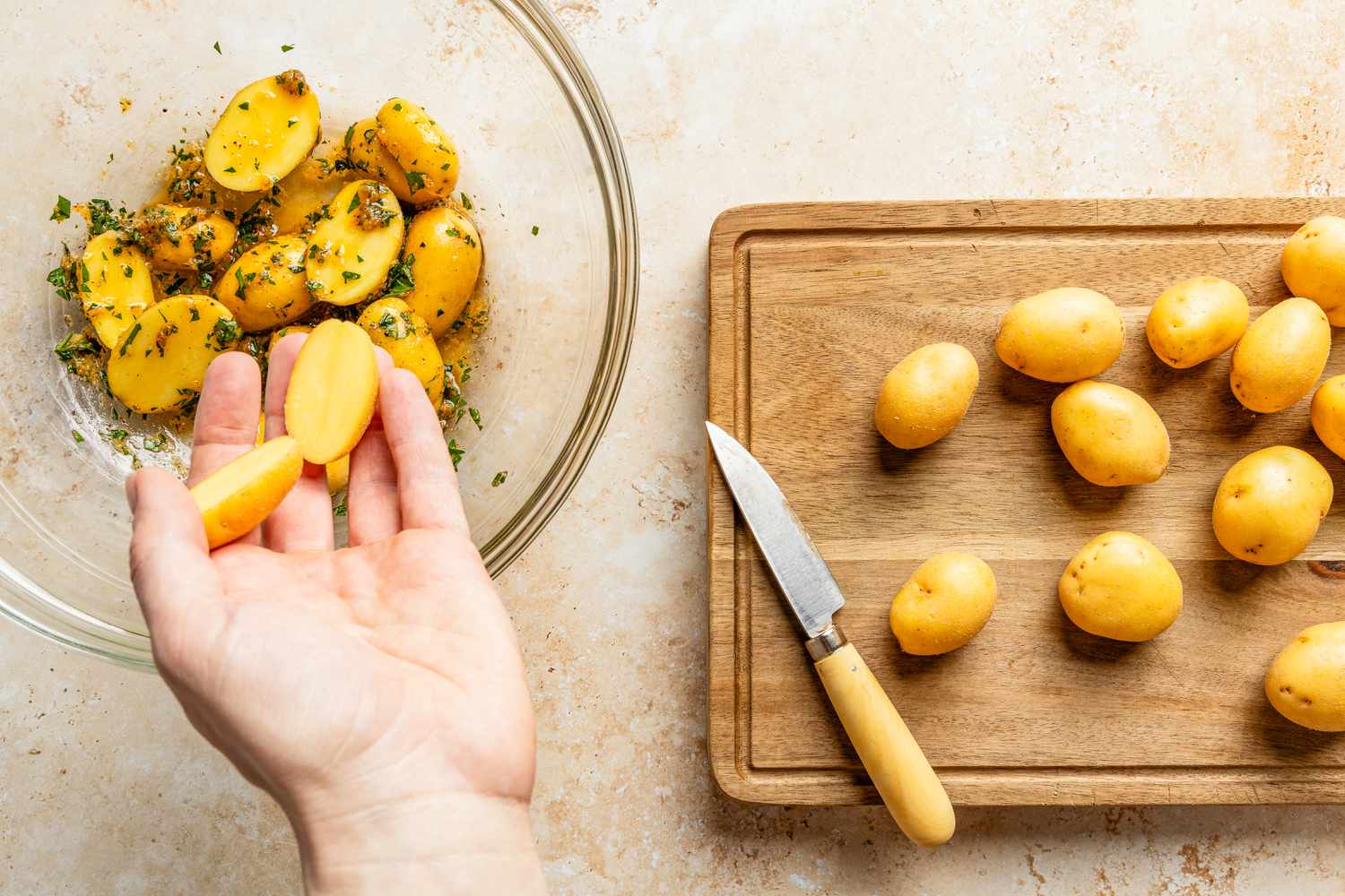 halved potatoes added to bowl of seasoning for crispy parmesan potatoes recipe