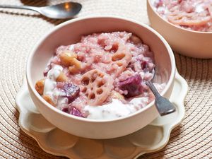Coconut rice pudding with lotus and sweet potato served in a bowl with a spoon.