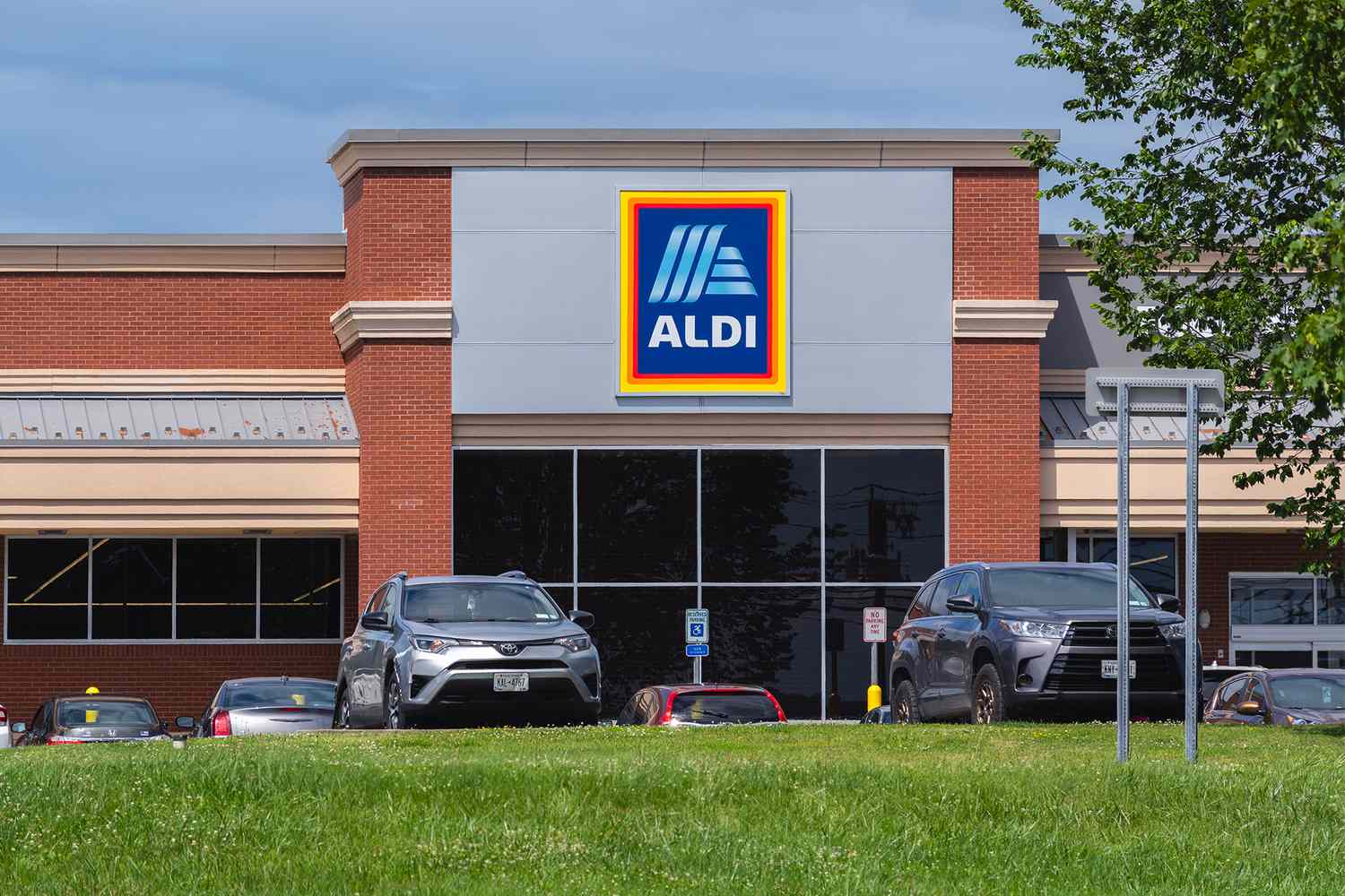 Front view of an Aldi store with cars parked in front featuring the logo prominently displayed on the building