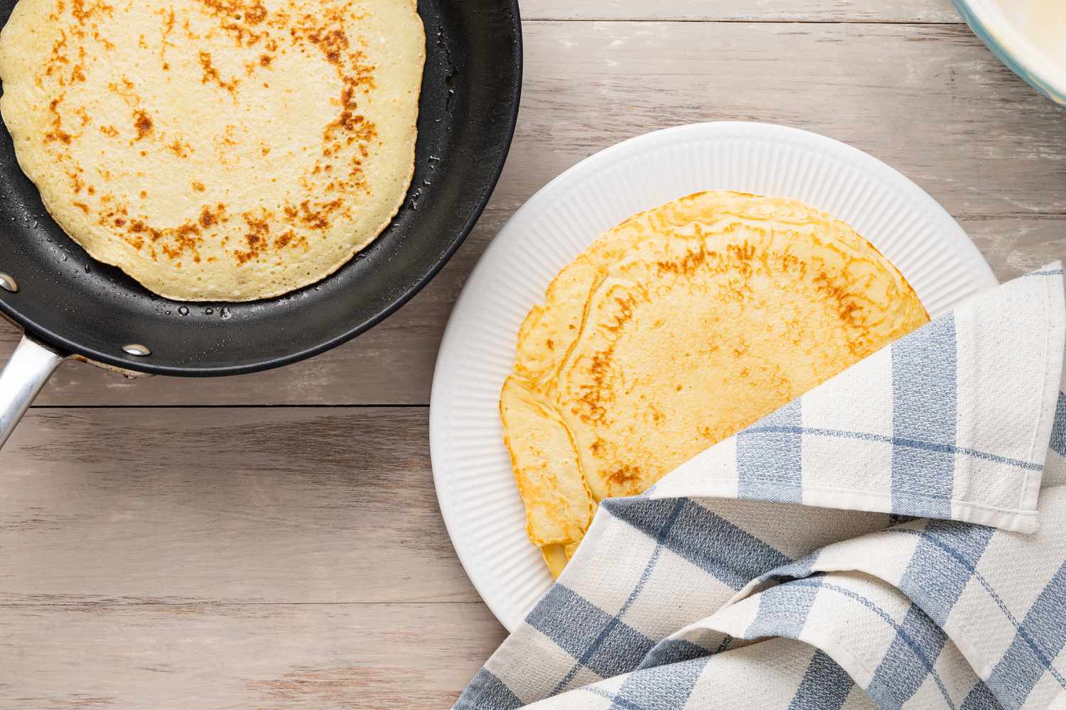 Cooked Pannenkoeken (Dutch Pancakes) placed on a plate and covered with a kitchen towel