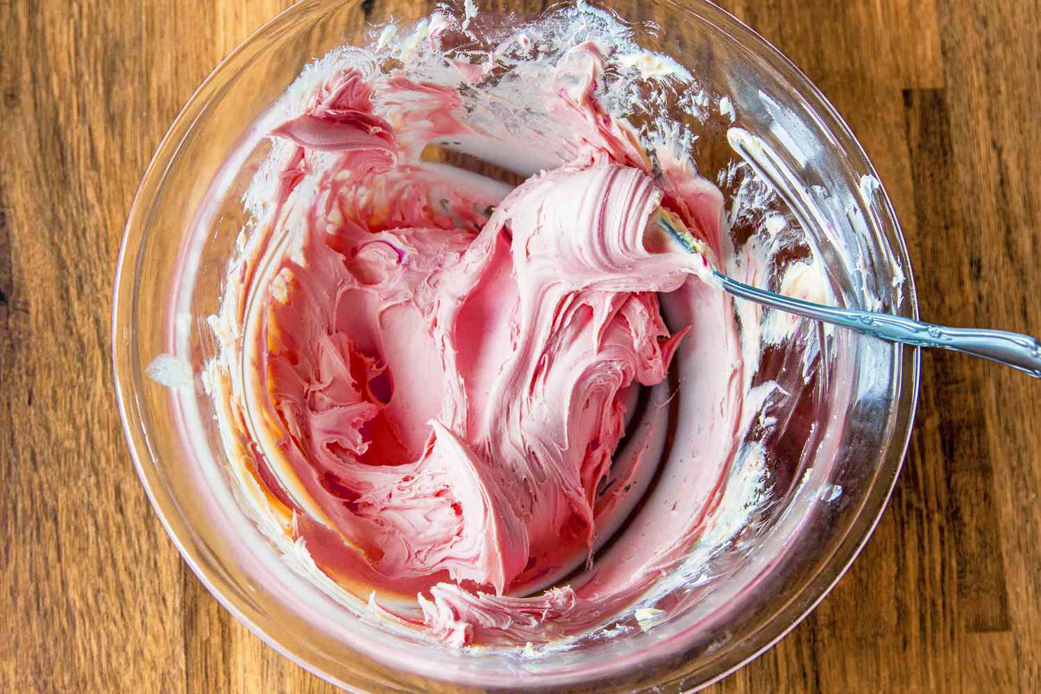 A glass bowl of strawberry butter with a spoon in it